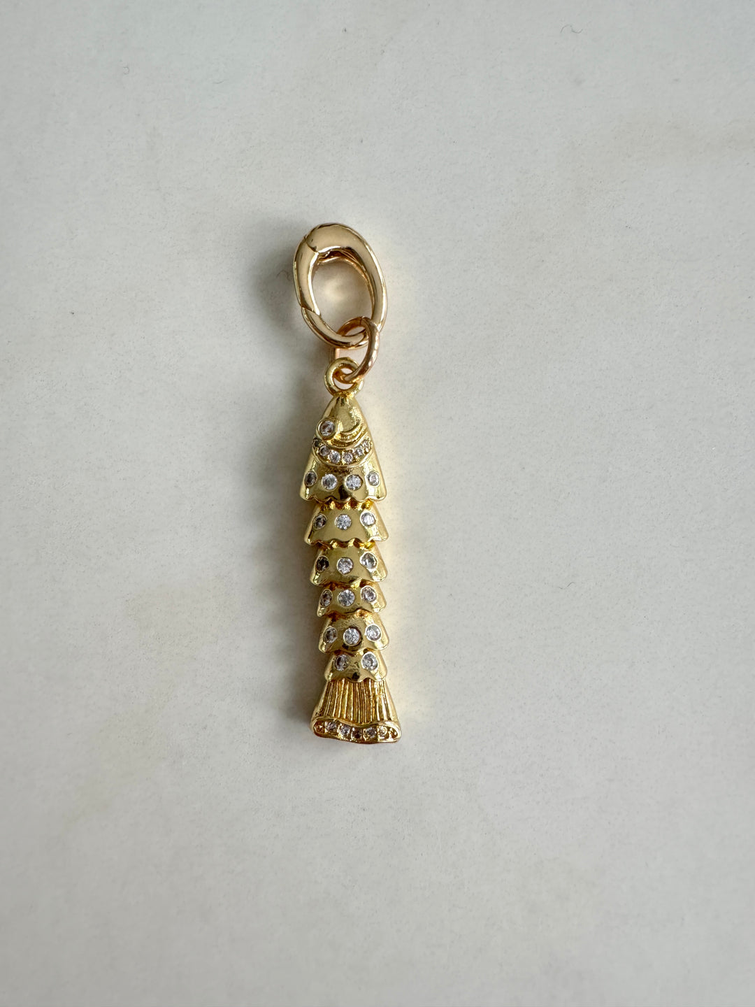 A gold-filled fish charm with clear crystals attached to a gold-filled push clasp, designed for use on a charm bracelet or necklace.