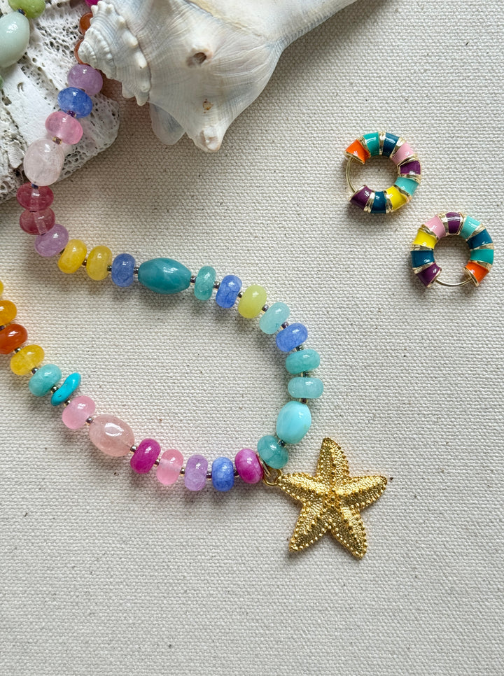 Beaded bracelet with starfish charm and matching earrings on a textured surface.