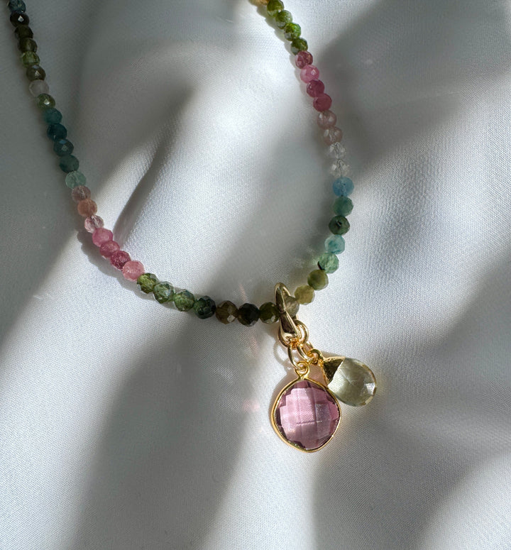 A colorful beaded necklace with a pink morganite pendant and green amethyst briolette charm, tourmaline stones
