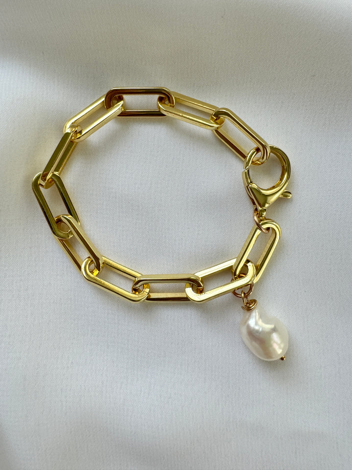 A gold-filled chunky link bracelet with a large spring closure and a single freshwater pearl pendant.