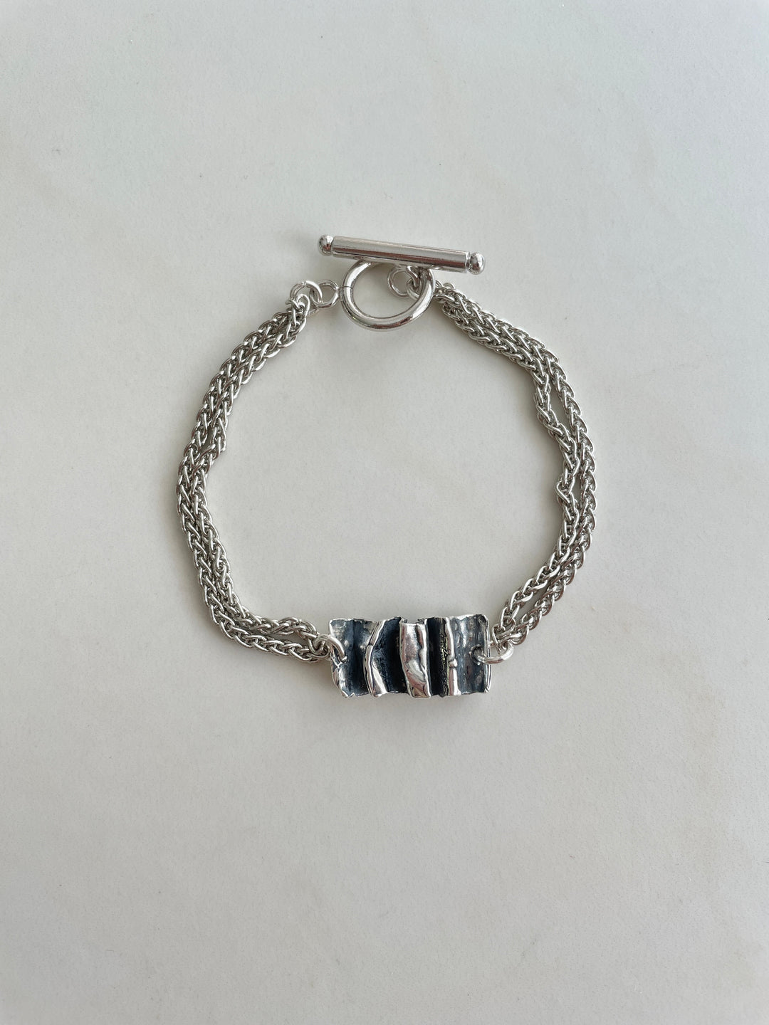A sterling silver bracelet with a lobster clasp closure and a pendant that resembles the Palazzo steps.