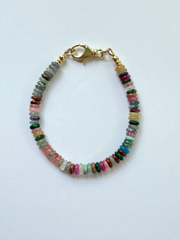 Multicolored beaded bracelet with gold clasp on a white background